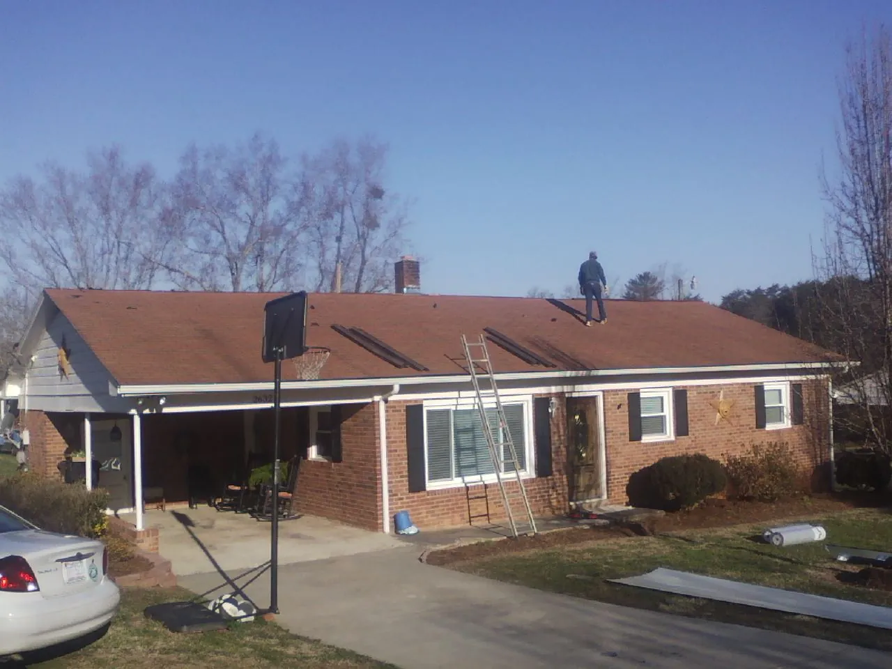 Roofer stripping a shingle roof on a brick ranch before metal panels in Hartford