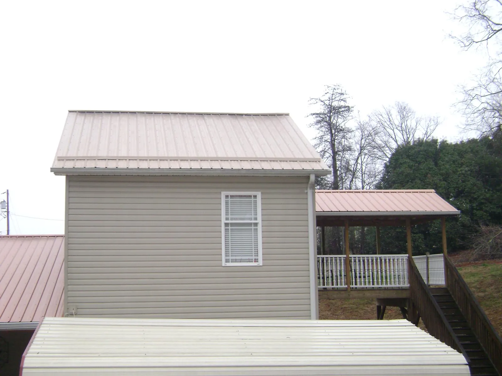 Tan metal roofs on a two story addition and attached porch, from a Roof Replacement job in Hartford